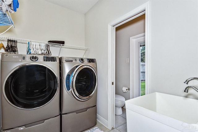 washroom with independent washer and dryer, sink, and light tile patterned floors