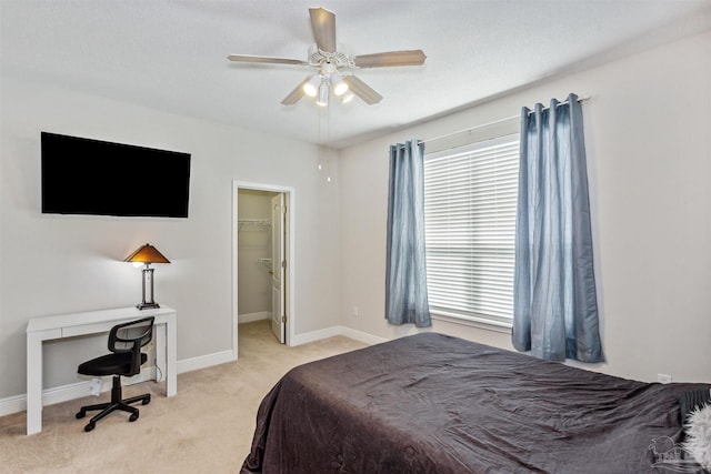 bedroom featuring light carpet, a spacious closet, ceiling fan, and a closet