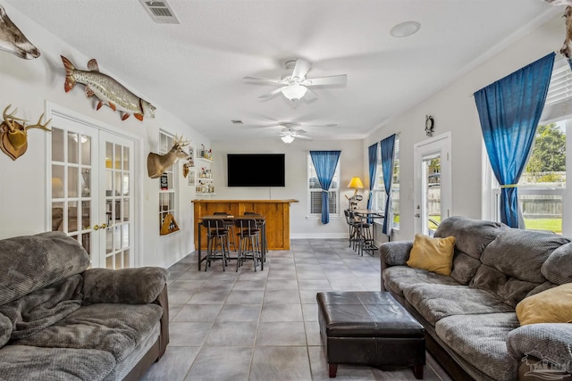 tiled living room with french doors, a textured ceiling, and ceiling fan