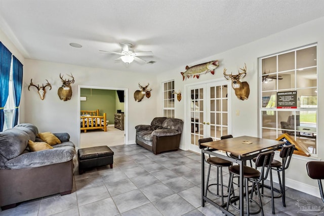 living room with french doors, a textured ceiling, and ceiling fan