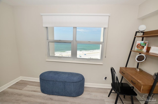 office with light wood-type flooring, a water view, and baseboards