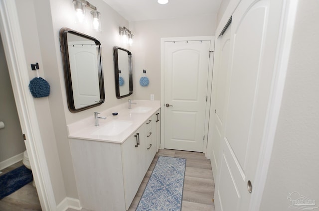 bathroom with dual vanity and hardwood / wood-style flooring