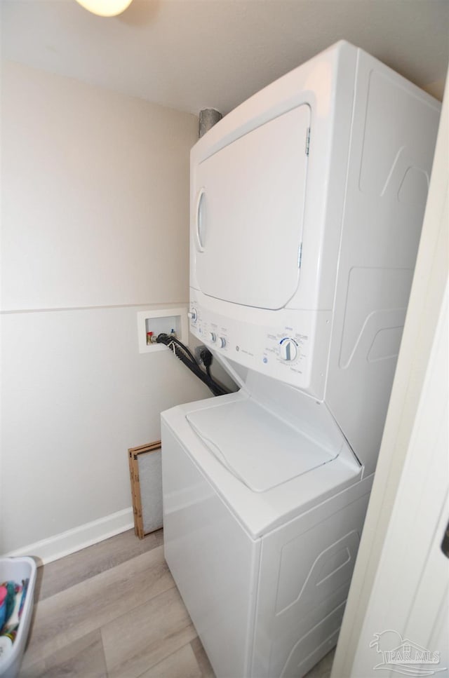 washroom with stacked washer and clothes dryer and light wood-type flooring