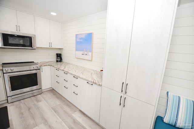 kitchen with light stone counters, stainless steel appliances, light hardwood / wood-style floors, and white cabinets