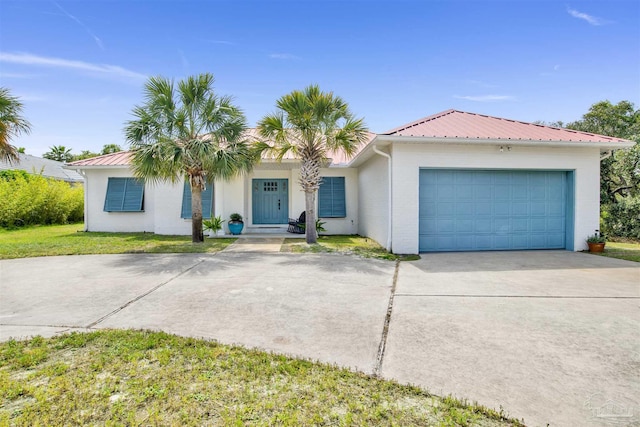 single story home featuring a garage, a front lawn, metal roof, and concrete driveway