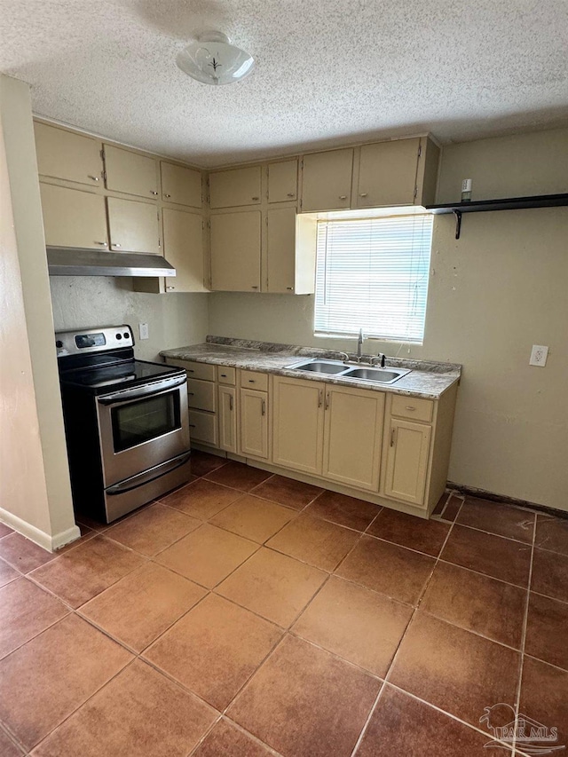 kitchen with electric stove, a sink, under cabinet range hood, cream cabinets, and a textured ceiling