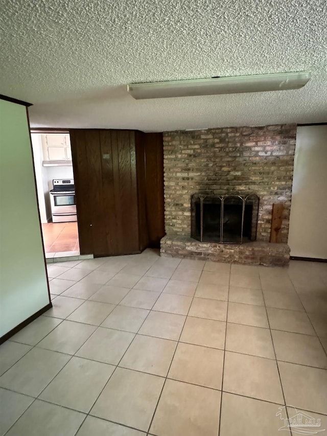 unfurnished living room featuring a textured ceiling, light tile patterned flooring, and a brick fireplace