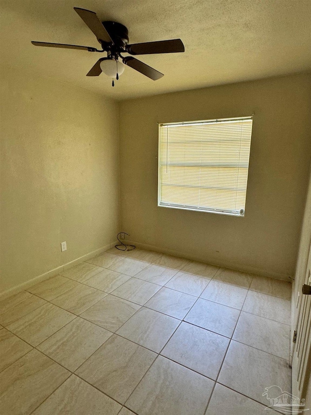 spare room featuring light tile patterned floors, a ceiling fan, and a textured ceiling