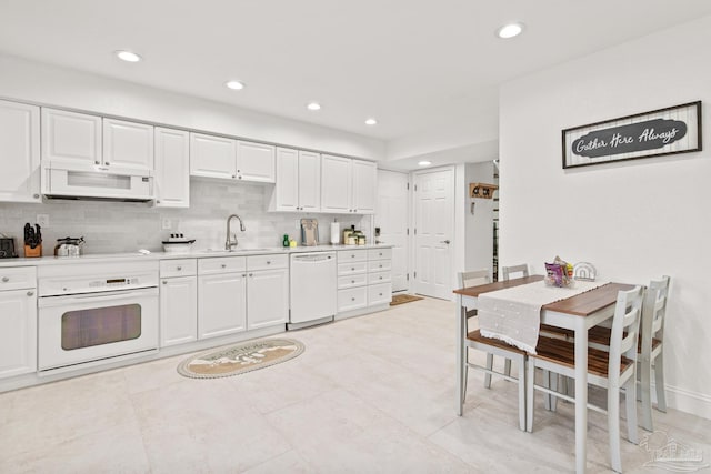 kitchen with decorative backsplash, white cabinetry, sink, and white appliances