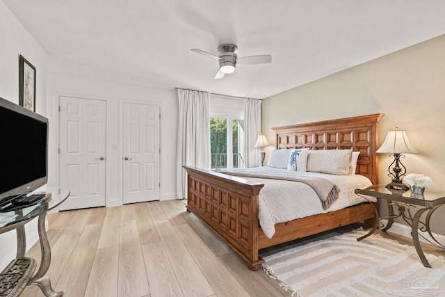 bedroom featuring ceiling fan, light hardwood / wood-style floors, and two closets