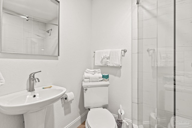 bathroom with toilet, a shower with shower door, and sink