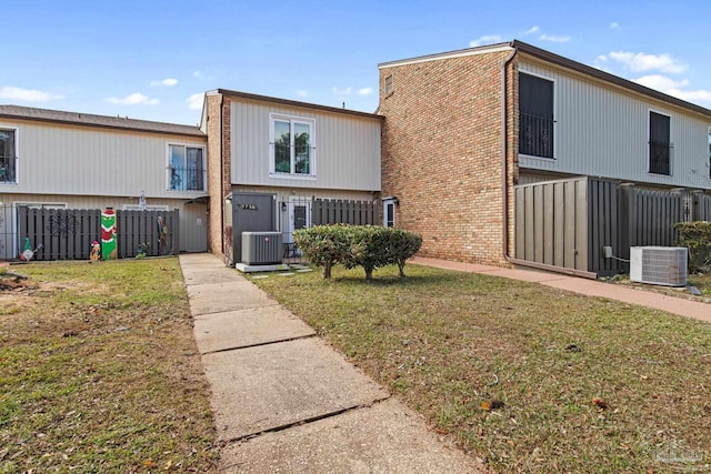 rear view of property with cooling unit and a lawn