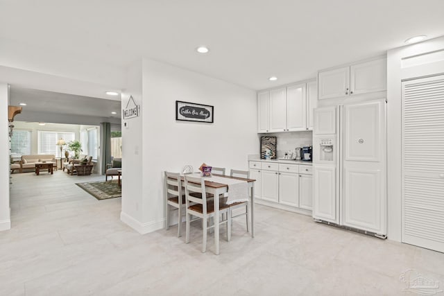 kitchen with decorative backsplash, white cabinetry, and paneled refrigerator