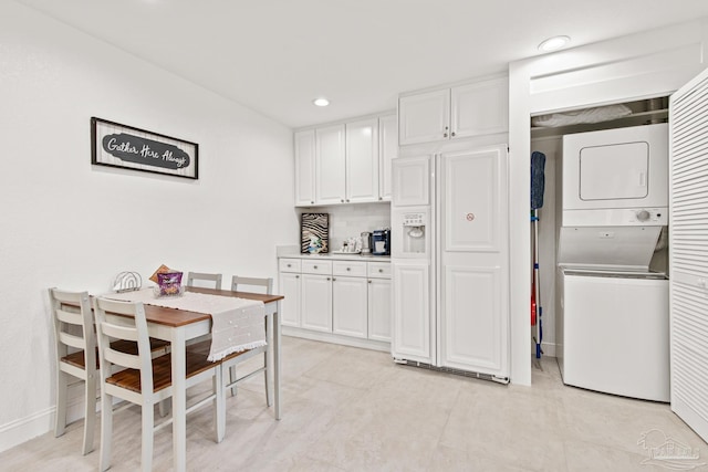 kitchen with paneled refrigerator, tasteful backsplash, white cabinetry, and stacked washer / drying machine