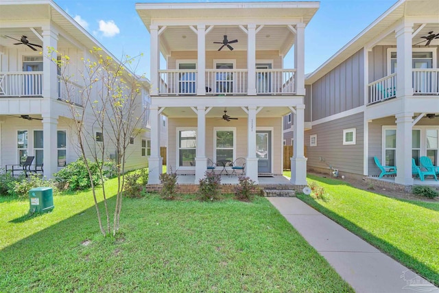 view of front facade with a balcony, ceiling fan, and a front lawn