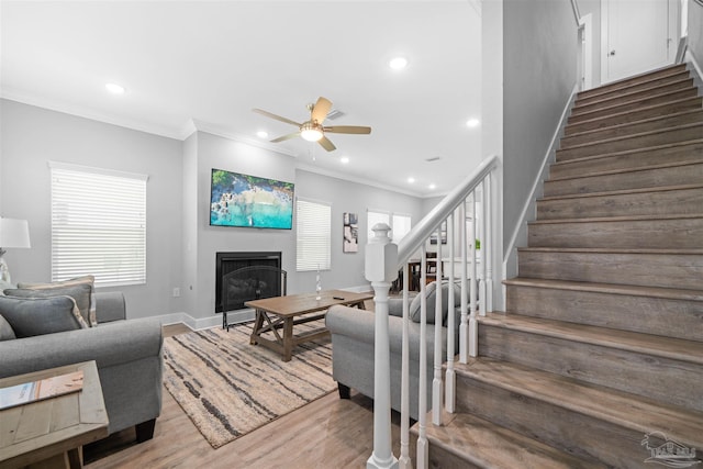 living room with light wood-type flooring, ornamental molding, and ceiling fan