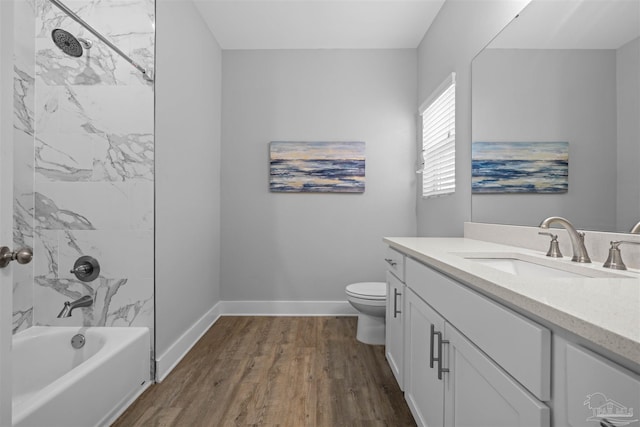 full bathroom featuring tiled shower / bath combo, hardwood / wood-style flooring, vanity, and toilet