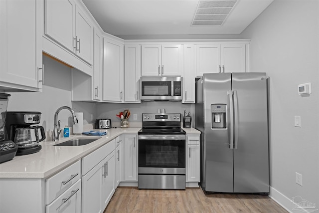 kitchen featuring white cabinets, appliances with stainless steel finishes, light wood-type flooring, and sink