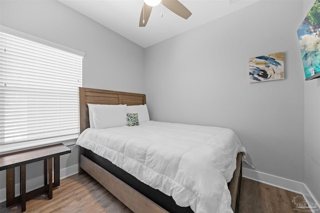 bedroom featuring multiple windows, hardwood / wood-style floors, and ceiling fan