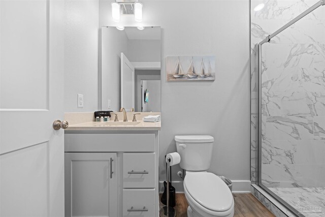 bathroom with hardwood / wood-style flooring, walk in shower, vanity, and toilet