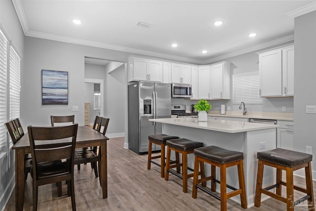 kitchen featuring stainless steel appliances, a center island, crown molding, and white cabinetry