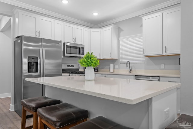 kitchen with ornamental molding, stainless steel appliances, white cabinets, and hardwood / wood-style floors