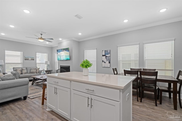 kitchen featuring light hardwood / wood-style flooring, white cabinets, ceiling fan, and ornamental molding