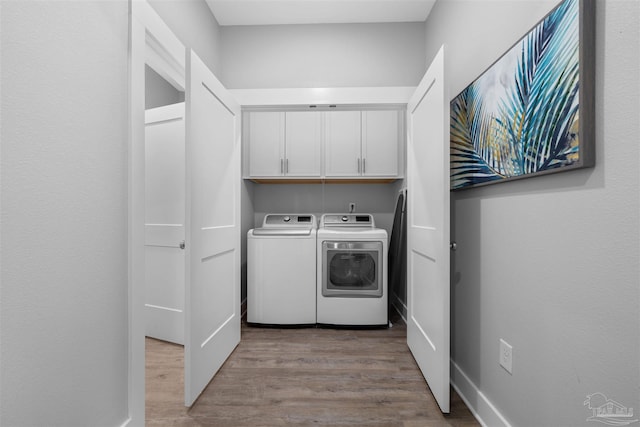 laundry room featuring cabinets, light wood-type flooring, and washer and dryer