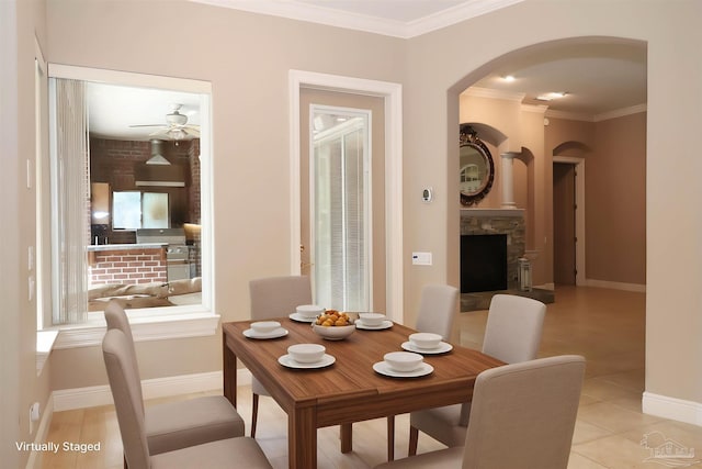 4436 Soundside Dr, Gulf Breeze, FL 32563 - dining area featuring arched walkways, crown molding, ceiling fan, a stone fireplace, and baseboards