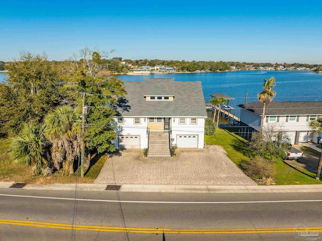 view of front of property with stairs, a water view, an attached garage, and driveway