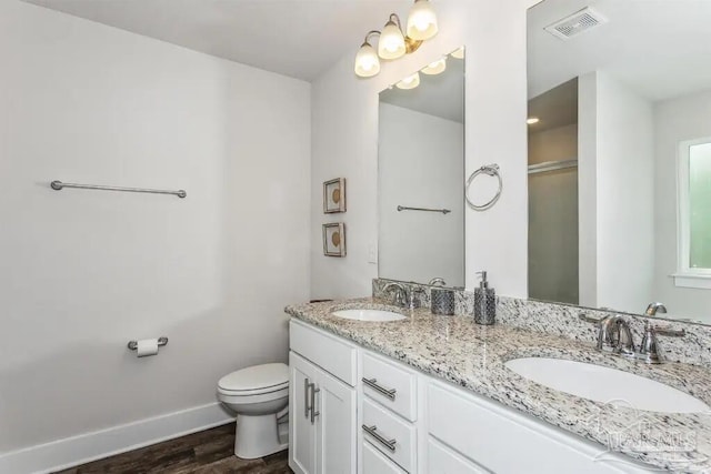 bathroom with hardwood / wood-style floors, vanity, toilet, and a shower with shower door