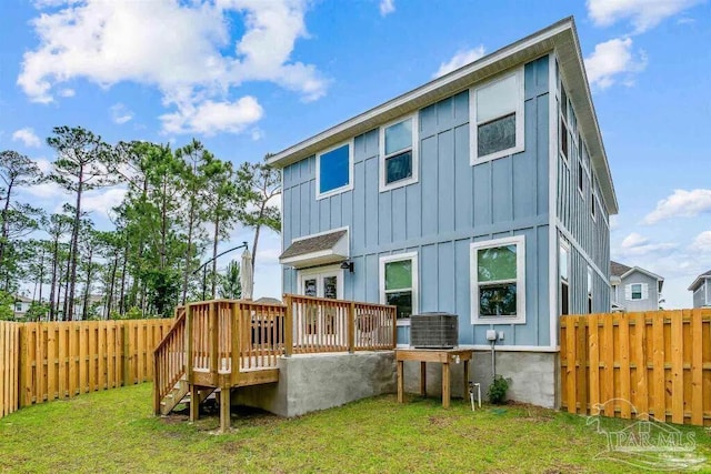 back of property featuring a lawn, central air condition unit, and a wooden deck