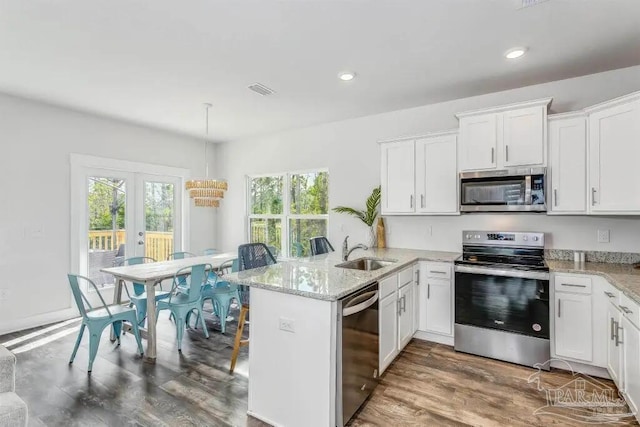 kitchen featuring kitchen peninsula, appliances with stainless steel finishes, white cabinetry, and plenty of natural light