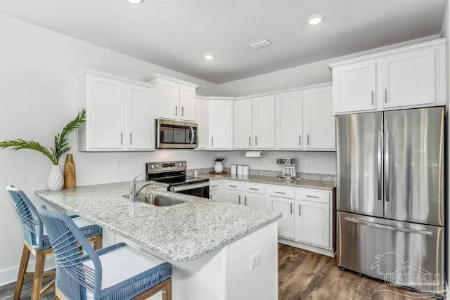 kitchen with kitchen peninsula, white cabinets, stainless steel appliances, and dark hardwood / wood-style floors