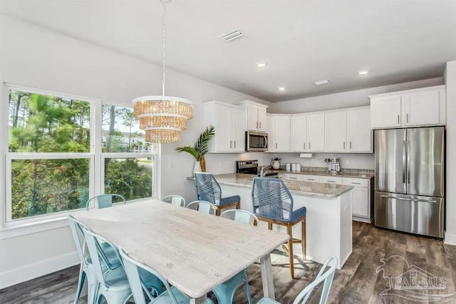 kitchen featuring white cabinetry, dark wood-type flooring, hanging light fixtures, and appliances with stainless steel finishes