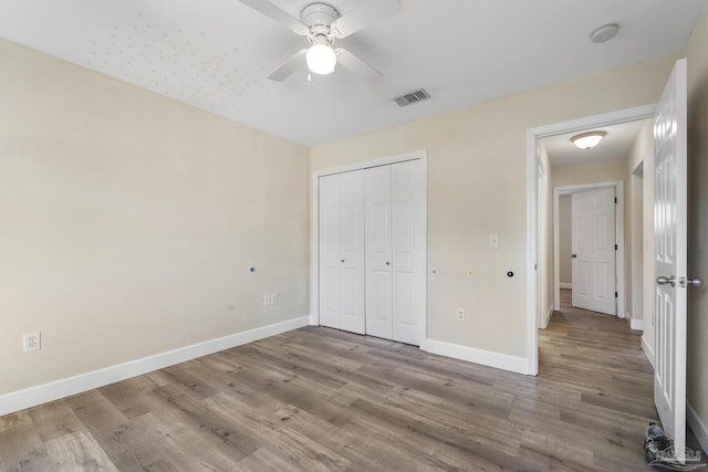 unfurnished bedroom featuring ceiling fan, a closet, and hardwood / wood-style flooring