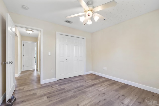 unfurnished bedroom with light wood-type flooring, ceiling fan, and a closet