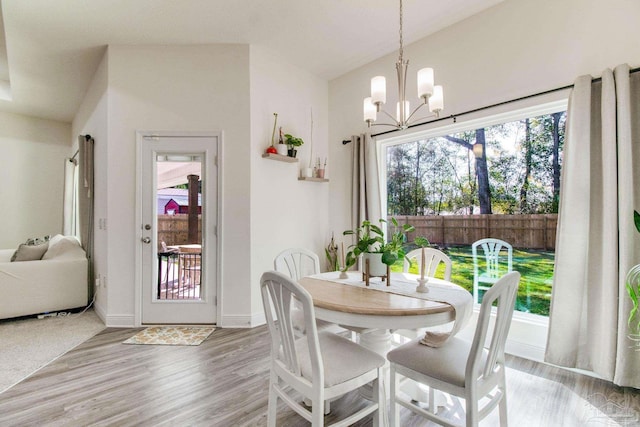 dining space featuring a chandelier, baseboards, light wood-style flooring, and vaulted ceiling