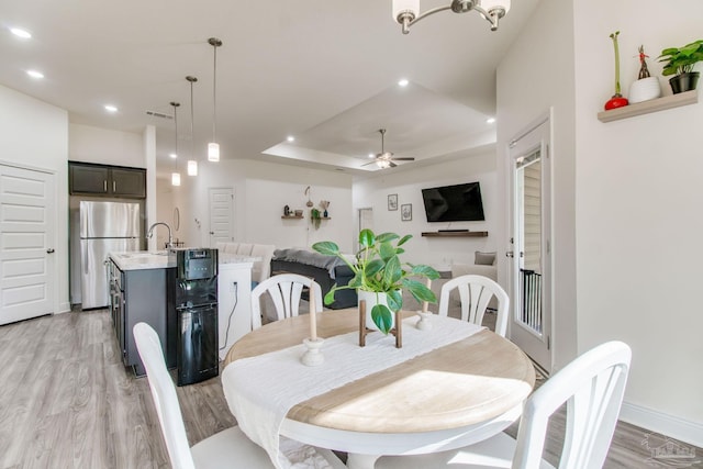 dining area with light wood-type flooring, visible vents, a tray ceiling, recessed lighting, and ceiling fan