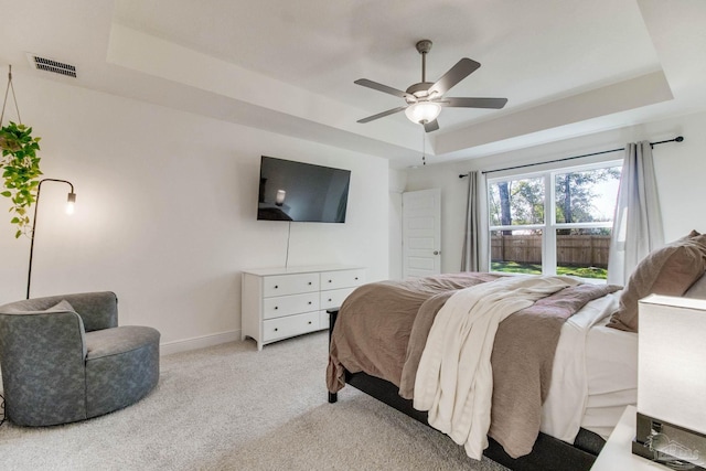 bedroom featuring baseboards, visible vents, ceiling fan, light carpet, and a raised ceiling