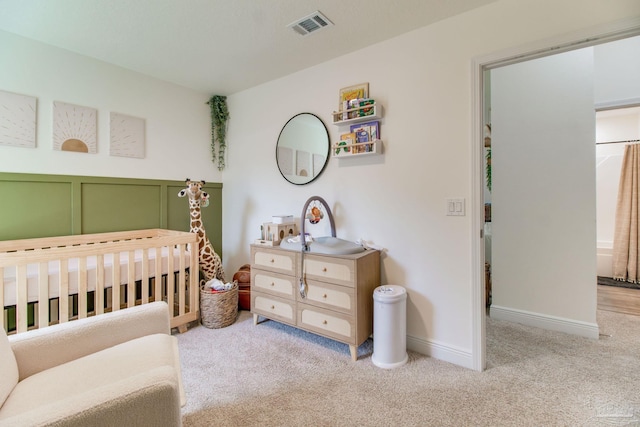 bedroom featuring visible vents, baseboards, a nursery area, and carpet flooring