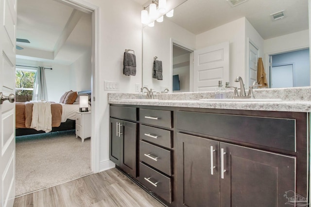 ensuite bathroom featuring a sink, double vanity, wood finished floors, and ensuite bathroom