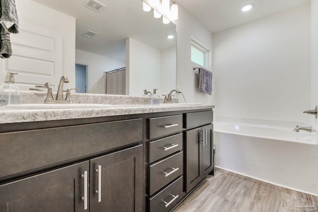 bathroom featuring a sink, visible vents, a garden tub, and wood finished floors