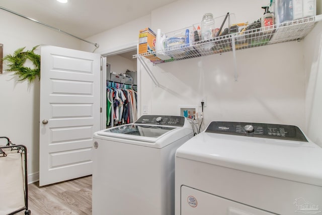 laundry area with washer and clothes dryer, laundry area, and light wood finished floors