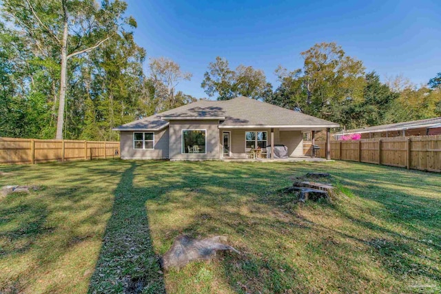 back of property with a patio area, a lawn, and a fenced backyard