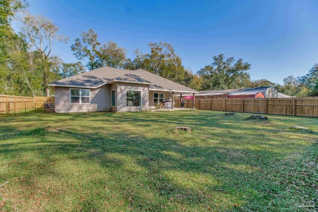 rear view of house featuring a yard and a fenced backyard