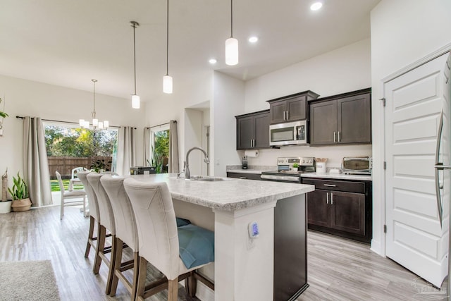 kitchen featuring a sink, dark brown cabinetry, appliances with stainless steel finishes, and a breakfast bar