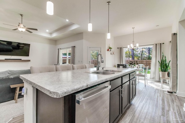 kitchen with a kitchen island with sink, a sink, light countertops, stainless steel dishwasher, and open floor plan