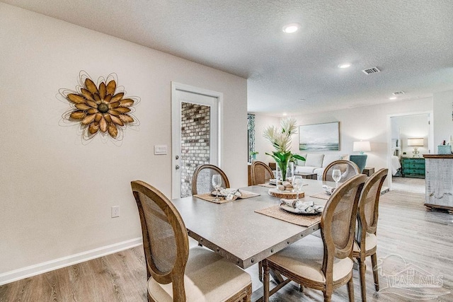 dining room with a textured ceiling, light wood-style flooring, recessed lighting, visible vents, and baseboards