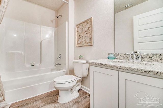 full bath with toilet, washtub / shower combination, vanity, a textured ceiling, and wood finished floors